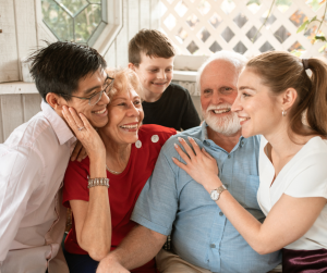 A joyful multigenerational family sitting closely together, smiling and embracing, symbolising love, connection, and the importance of planning family wills.
