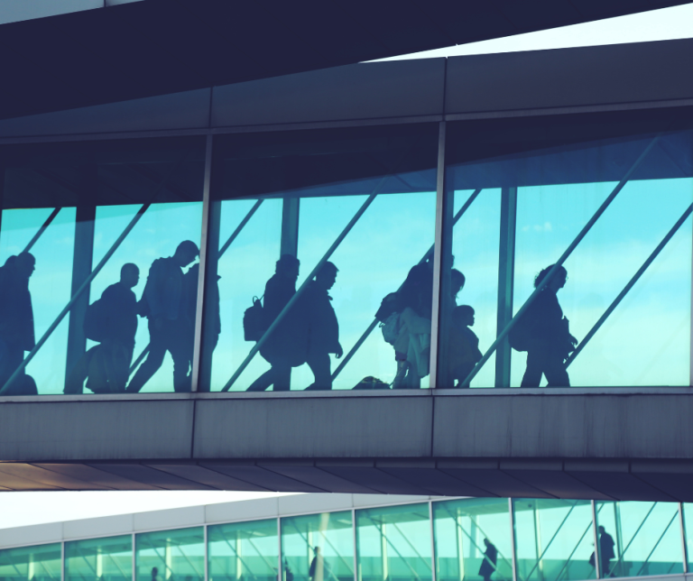 Business travellers walking through airport terminal, representing companies working with sponsor licence solicitors to hire overseas workers legally in the UK.