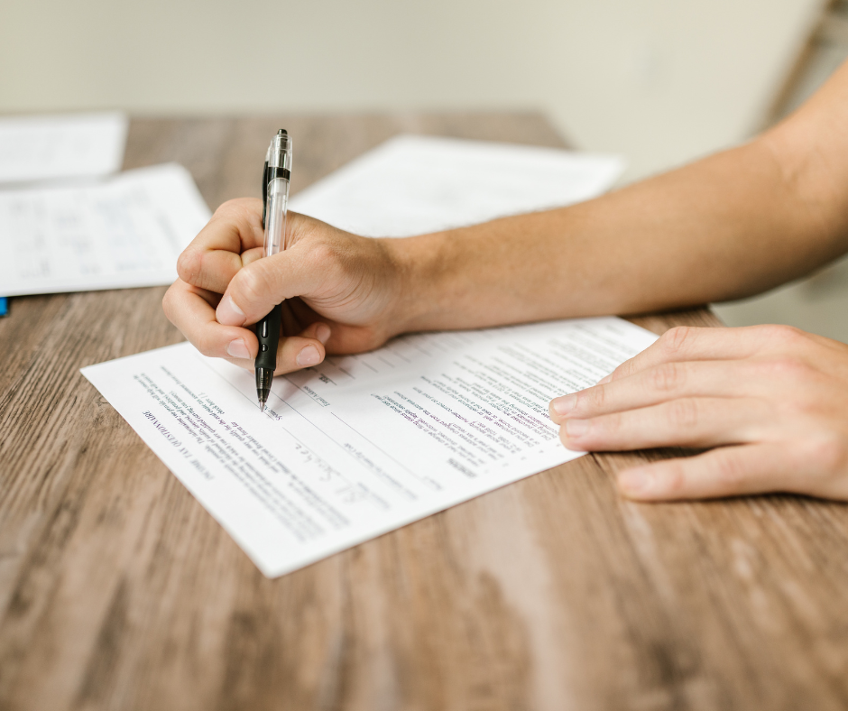 Close-up of a person completing and signing a document, illustrating paperwork associated with the Statement of Changes to the UK Immigration Rules.