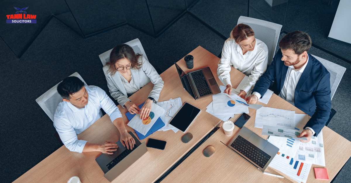 Overhead view of business professionals reviewing documents and discussing workplace compliance, illustrating employer responsibilities under the Fair Work Agency.